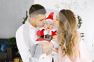 Family celebrates Christmas at home in the living room near the Christmas tree. Happy mom, dad and son enjoy their vacation togeth