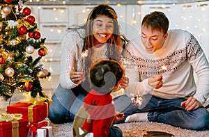 A young family and a child create a festive mood by lighting sparklers and spending time together