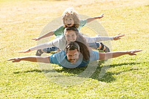 Young family with child having fun in nature. Fly concept, little boy is sitting pickaback while imitating the flight.