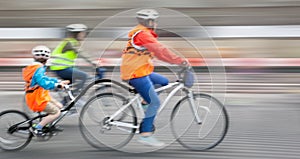 Young family with a child ride a bikes on a city streets