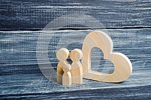 A young family with a child is standing near a wooden heart. Love and loyalty, a strong young family. Family relationships. Civil