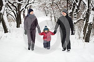 A young family with a child walking through a snow-covered forest.