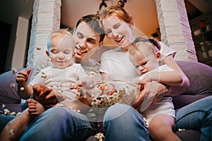 Young family with children eating popcorn on the couch.