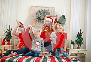 Young family with children having fun at home fighting pillows on bed in christmas, happy lifestyle on holidays parents with kids