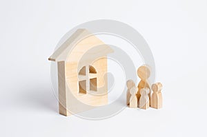 A young family with children is standing near a wooden house. The concept of a strong family, the continuation of the family.