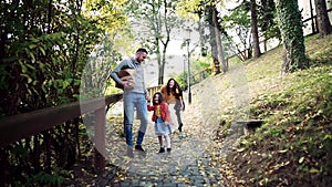 A young family with children walking in park in autumn. Slow motion.