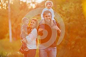 Young family with children walking in park. Father, mother and two sons