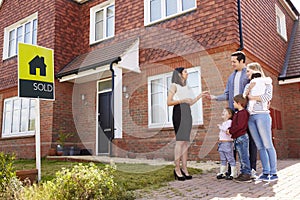 Young Family Collecting Keys To New Home From Realtor