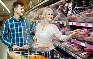 Young family couple choosing chilled meat