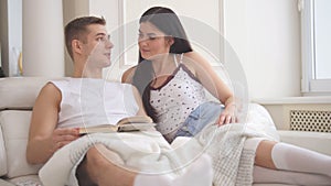 Young family couple - man and woman sitting together on the couch and spending time at home