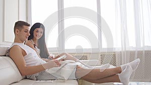 Young family couple - man and woman sitting together on the couch and spending time at home