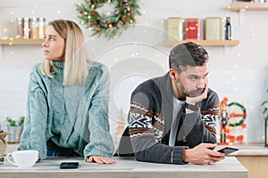 Young family couple quarreled over mobile phone and social networks, man and woman sad during the New Year holidays and Christmas