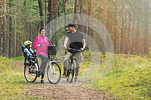 Young family cycling on forest trail with kid in bike child seat. active sports outdoor recreation