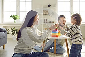 Young family with a daughter playing an educational pyramid game at home together.