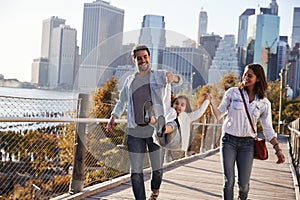 Young family with daughter taking a walk on footbridge