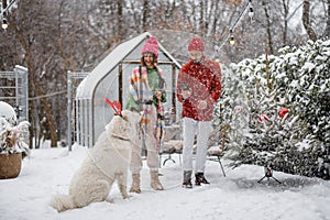 Young family with a dog at snowy backyard during winter holidays