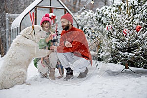 Young family with a dog at snowy backyard during winter holidays