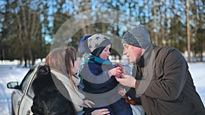 A young family is eating tangerines during a picnic on a winter day.