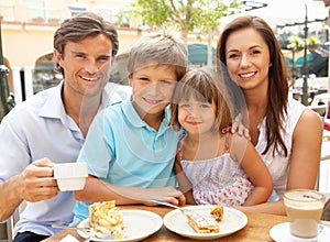 Young Family Enjoying Cup Of Coffee And Cake