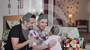 A young family - Father, mother, and an infant spending time in their bedroom