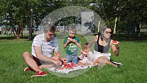 Young Family of Four Eating Watermelon Outdoors