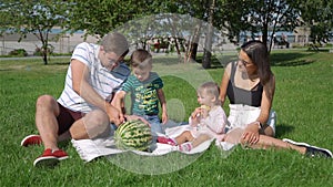 Young Family of Four Having Picnic in City Park