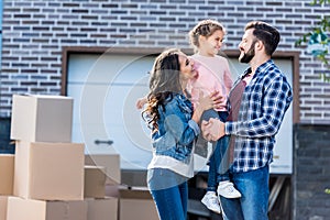 young family in front of new house with many boxes standing on pathway