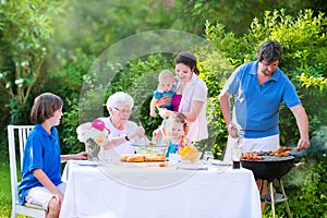 Young family grilling meat for lunch with grandmother