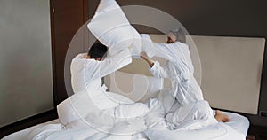 Young family has pillow fight playing on comfortable bed