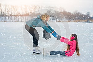 Young family have fun on the ice area in a snowy park
