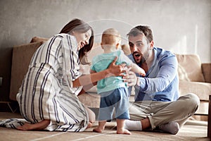 Young family is having fun playing with a baby at home