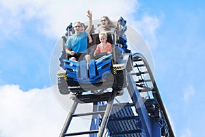 Young family having fun riding a rollercoaster at a theme park