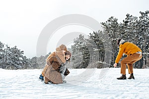 Young family having fun in winter snowy forest