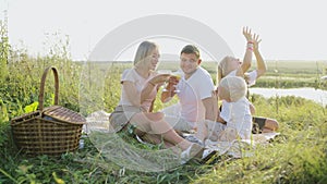 Young family having a picnic by the river. Happy family at a picnic. Mom, dad, son and daughter had a picnic on the