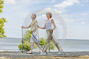 Young family hiking in the nature nordic walking near the lake