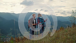 Young family hiking together on mountains nature sunset. Couple talk on hiking.