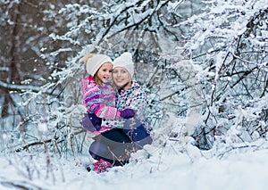 Young family hugging and laughing on snowy winter walk in nature.