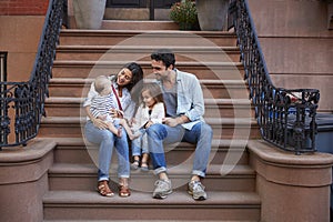 Young family with kids sitting on front stoops