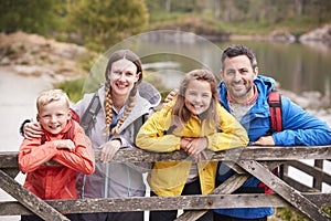 Young family leaning on a wooden fence in the countryside, looking at camera, close up