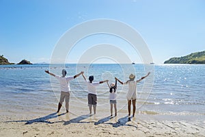 Young family lifting hands together on the beach