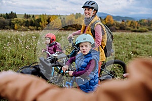 Young family with little children preparing for bicycle ride in nature. Healthy lifestyle concept.