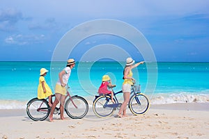 Young family with little kids ride bikes on a tropical exotic beach