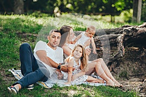 Young family with little kids in summer park on sunny day