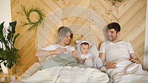 A young family with little son play on bed in the bedroom