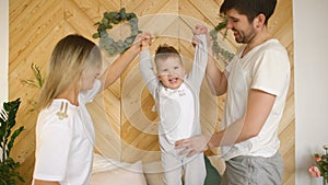 A young family with little son play on bed in the bedroom