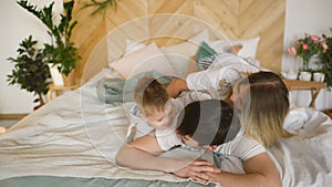 A young family with little son play on bed in the bedroom