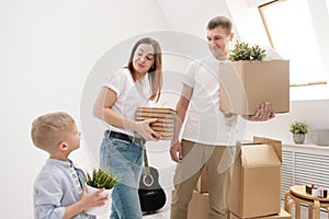 Young family, man woman and child son in new apartments. Boxes with cargo on a white background.