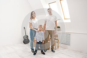 Young family, man woman and child son in new apartments. Boxes with cargo on a white background.