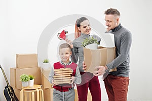 Young family, man woman and child son in new apartments. Boxes with cargo on a white background.