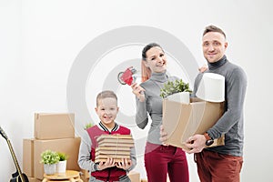 Young family, man woman and child son in new apartments. Boxes with cargo on a white background.